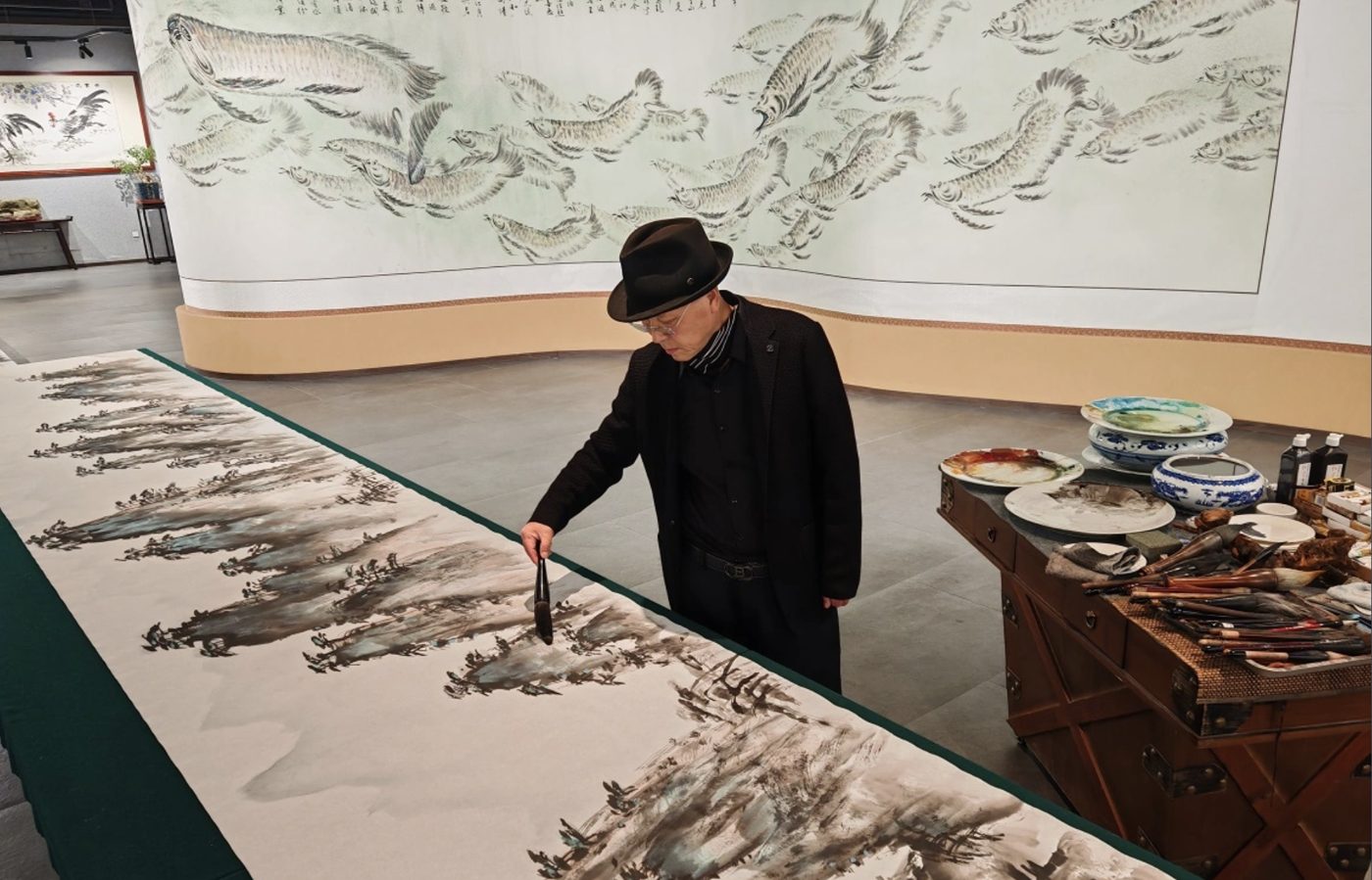 Xue Jiuzhou painting a long ink scroll in the gallery